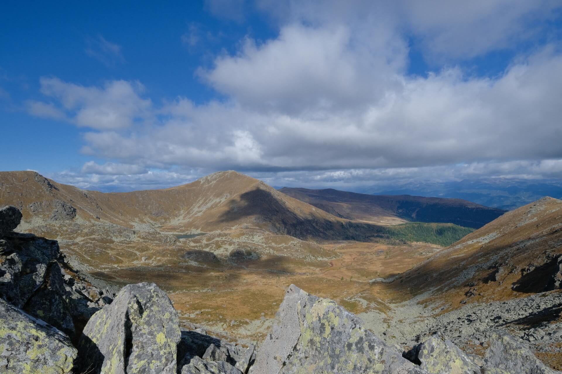 Weite Berglandschaft mit kahlen Gipfeln unter Wolkenhimmel
