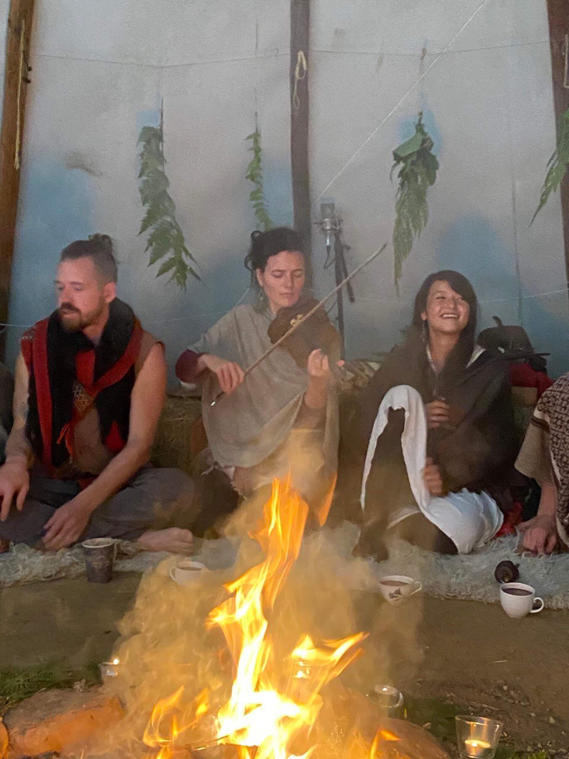 Drei Musizierende am Feuer im Tipi, in der Mitte eine Violinistin